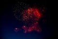 Red and orange fireworks with green sparks inside and smoke, below you can see small fireworks against the night sky Royalty Free Stock Photo
