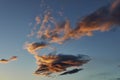 Some Scattered clouds in a deep blue sky tinged with red and orange from the setting sun in Scotland.