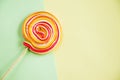 Red-orange twisted lollypop on the bicolor background with a copy space