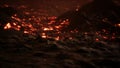 Red Orange vibrant Molten Lava flowing onto grey lavafield and glossy rocky land Royalty Free Stock Photo