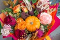 Red orange yellow autumn bouquet with rose flowers, fall leaves and pumpkin close up