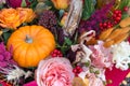 Red orange yellow autumn bouquet with rose flowers, fall leaves and pumpkin close up background