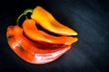 Red, Orange and yellow organic sweet pointed peppers on a blackboard, natural light