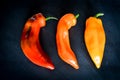 Red, Orange and yellow organic sweet pointed peppers on a blackboard, natural light