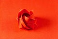 Red origami rose on red background