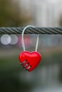 Red padlock on a rope, bokeh of evening city lights. Symbol of love. Romantic concept. Metal heart on a cable on river bridge. Hea Royalty Free Stock Photo