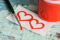 Red paint gouache in a jar, brush. painted two hearts on a scrap of paper. on a textured old cracked blue green background on a wo Royalty Free Stock Photo