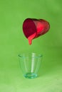Red paint pouring to a blue glass from a flying red one Royalty Free Stock Photo