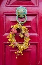 Red painted door with old style lion knocker and wreath of flowers Royalty Free Stock Photo