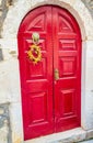 Red painted door with old style lion knocker and wreath of flowers Royalty Free Stock Photo