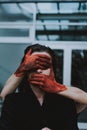 Red painted hands covering the eyes and mouth of a female. Concept of silence