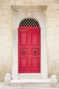 Red painted old wooden door with black iron handle in medieval city street Royalty Free Stock Photo
