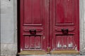 Red painted wooden double door with vintage handles. Shabby surface of antique gate. Scratched weathered wood textures. Royalty Free Stock Photo