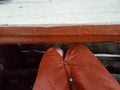 Red pants rest under weathered wooden bench. Royalty Free Stock Photo