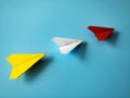 Red paper airplane origami leading white and yellow airplanes on blue background with customizable space for text Royalty Free Stock Photo