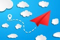 red paper airplane with start point, dah line trace and white clouds on blue air background. Clear sky travel background Royalty Free Stock Photo