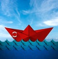 Red Paper Boat with Lifebuoy in the Blue Waves of the Sea Royalty Free Stock Photo