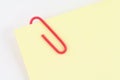 Red paper clip with yellow notepaper Royalty Free Stock Photo