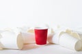 Red paper cup stands among lying white paper cups Royalty Free Stock Photo