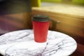 Red paper disposable cup of coffee to takeaway on marble table i