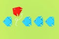 Red paper fish swimming out of line of blue fish. Concept for new business strategies, discovery, and different thinking