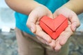 A red paper fold as heart shape in woman hand. A woman holding origami heart with two hand. Love and gift concept for valentine. Royalty Free Stock Photo