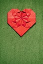 Red paper folded origami handmade heart on green knitted nice sweater background. Valentines day cozy vertical postcard template. Royalty Free Stock Photo