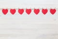 Red paper heart hanging on brown nature rope with mini clothespin. On white wooden plank. For Valentine day and love concept Royalty Free Stock Photo