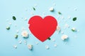 Red paper heart, white roses and petals on blue pastel background. Spring or summer concept. Creative layout. Top view, flat lay Royalty Free Stock Photo