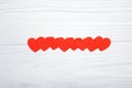 Red paper hearts hanging on white wooden background