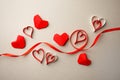 Red paper hearts and silk ribbon on gray background. Valentine`s Day absctract. Symbol of love. Copy space, flat lay