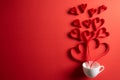 Red paper hearts splash out from white coffee cup on red paper background. Love and Valentine`s day concept Royalty Free Stock Photo