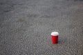 Red paper, plastic coffee cup with a white lid on gray asphalt Royalty Free Stock Photo