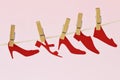 Red paper shoes cut-out hanging on clothesline - Concept of femicide and violence against women Royalty Free Stock Photo