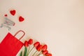 Red paper shopping bag, a bouquet of tulips and a shopping cart Royalty Free Stock Photo