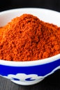 Red paprika powder in a porcelain bowl. Dark background, close up Royalty Free Stock Photo