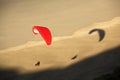 A red paraglider flies over a beach Royalty Free Stock Photo