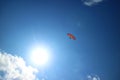 Red Paraglider Flying in the Blue Sky with the Dazzling Sun Royalty Free Stock Photo