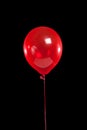 Red party balloon on black