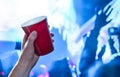 Red party cup in hand in night club, bar or college student event. Plastic beer mug. People having fun in blue nightclub disco. Royalty Free Stock Photo