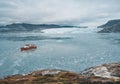 Red Passenger cruise ship sailing through the icy waters of Qasigiannguit, Greenland with Eqip Sermia Eqi Glacier in Royalty Free Stock Photo