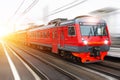 Red passenger train with headlights on rushing through the railway in the evening. Royalty Free Stock Photo