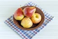 Red pears and apple in brown plate on white wooden table. Royalty Free Stock Photo