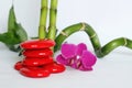 Red pebbles arranged in zen lifestyle with a dark pink orchids on the right side of the bamboo straight and twisted the whole on w Royalty Free Stock Photo