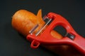 Red Peeler and carrot isolated on dark/black background .