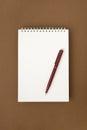 Red pen on Blank white spiral notebook on brown surface Royalty Free Stock Photo