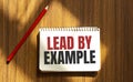 Red pen and notepad with text LEAD BY EXAMPLE in the white background Royalty Free Stock Photo