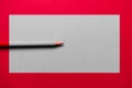 Red pencil over a red background, with a grey rectangle in the middle