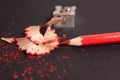 Red pencil with pencil shavings and pencil sharpener up close Royalty Free Stock Photo