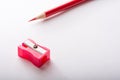 Red Pencil sharpener close-up and red pencil on white paper sheet. stationery. Royalty Free Stock Photo